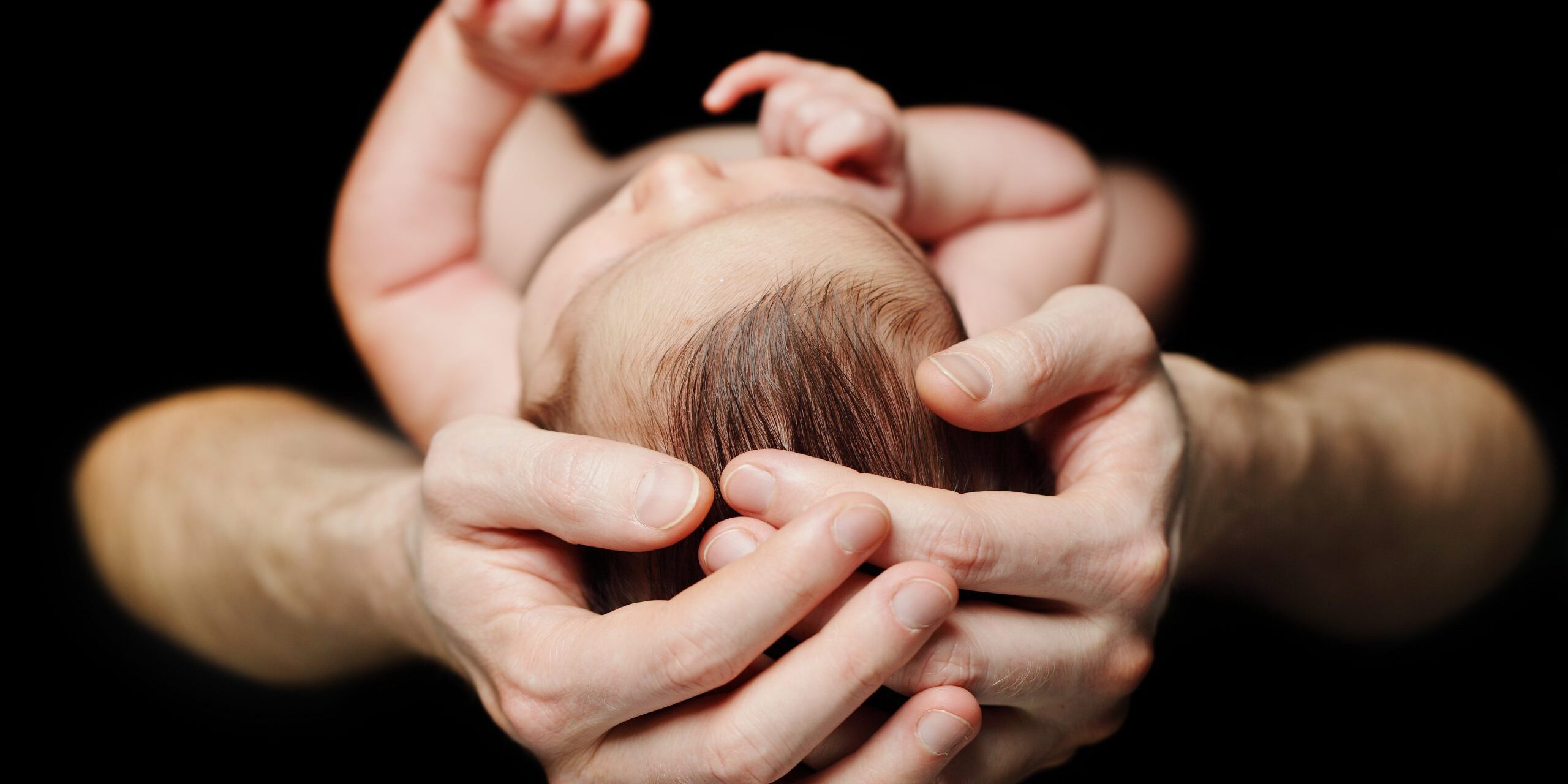 Male hands with baby - parental love and care